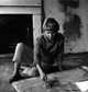 Black and white portrait of Sandra Blow seated on the floor, painting in her studio — a candid moment capturing the artist at work.